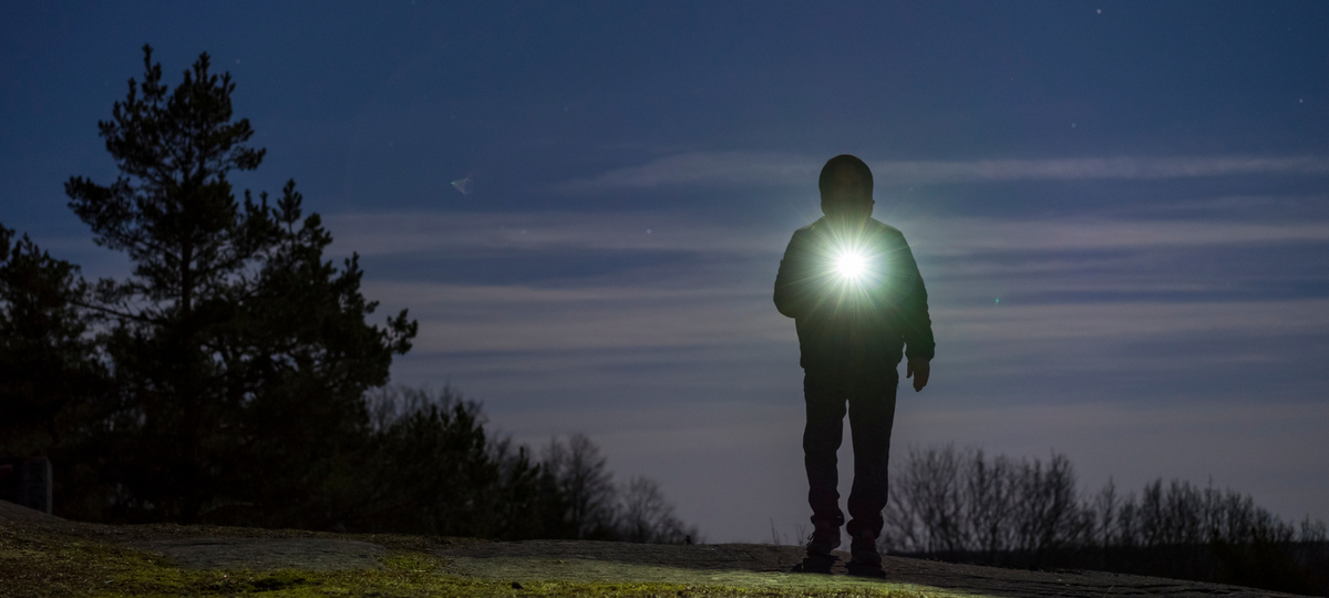 A man was walking at night using a flashlight.